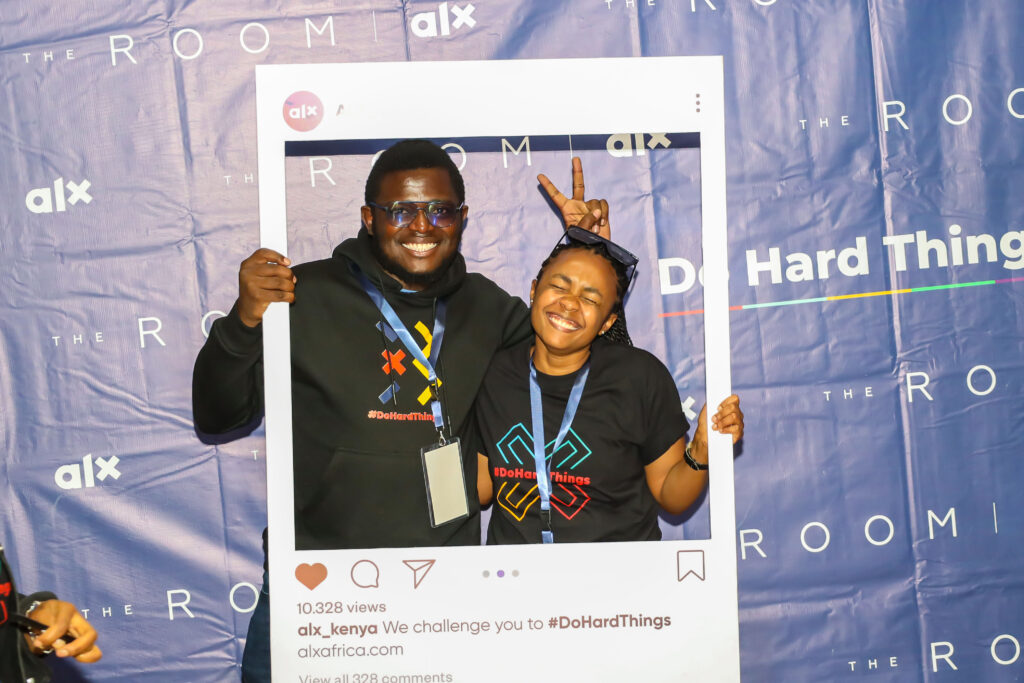 Two ALX learners posing playfully through a frame photo prop at Nairobi's Karibu ceremony