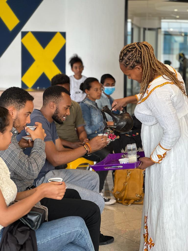 Lady serving coffee to ALX learners at the Nu Buna Tetu community event at the Addis Capstone Hub in Ethiopia
