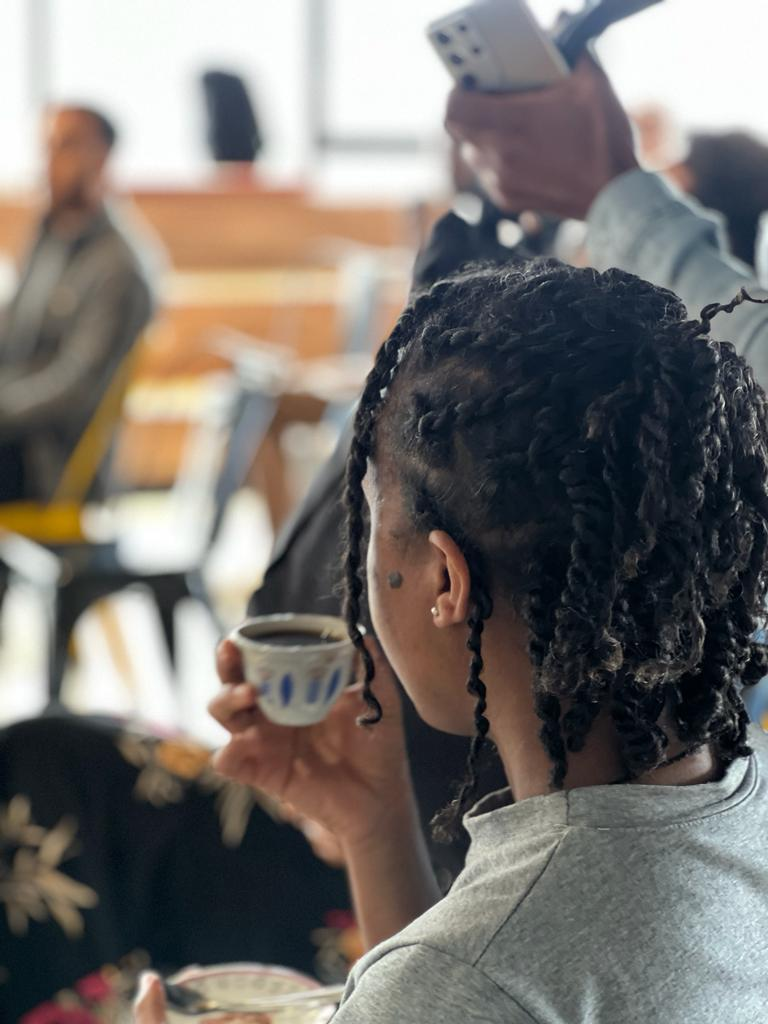ALX learner drinking coffee at the Nu Buna Tetu community event at the Addis Capstone Hub in Ethiopia