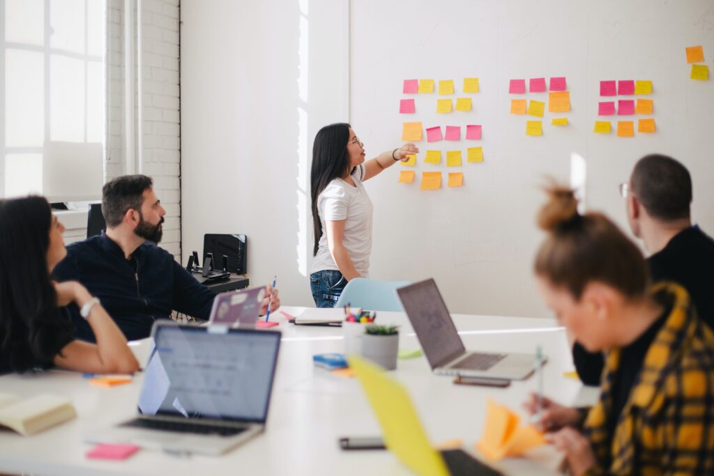 Woman placing sticky notes on a board in what appears to be a classroom.