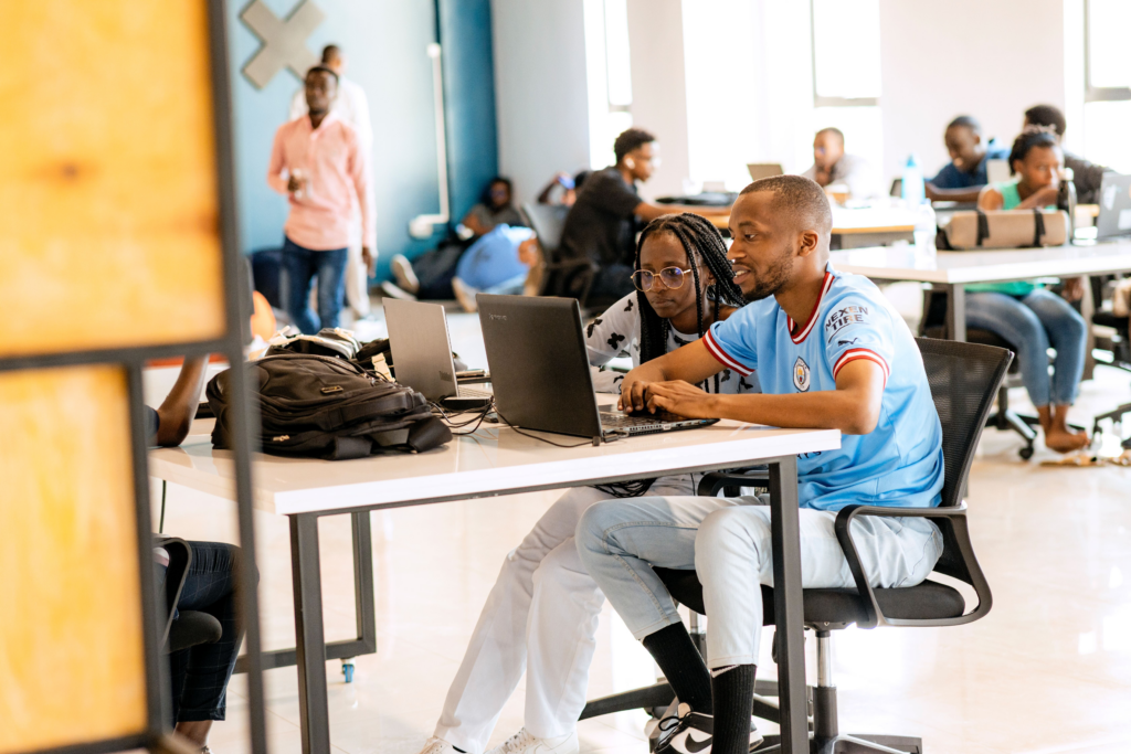 Two ALX learners working on their laptops at the Kigali hub - Discovering ALX’s Impact: Special Guests Visit