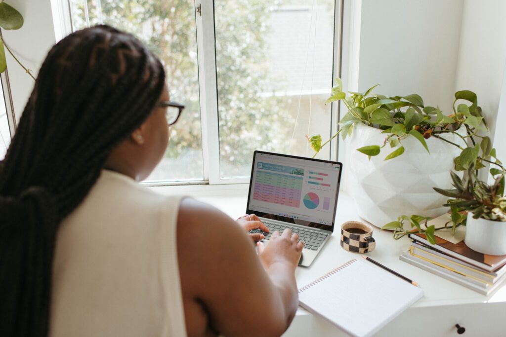 A woman sitting down behind her computer looking at data visualisations on her screen.