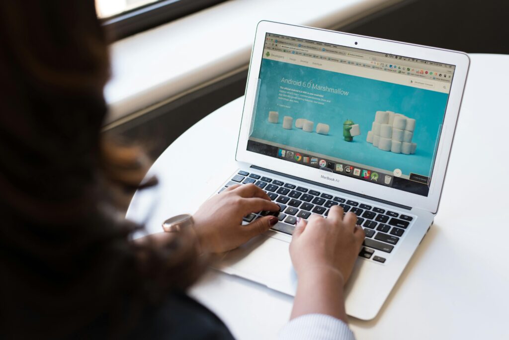 Woman sitting at a table using a macbook pro to do some web development work.