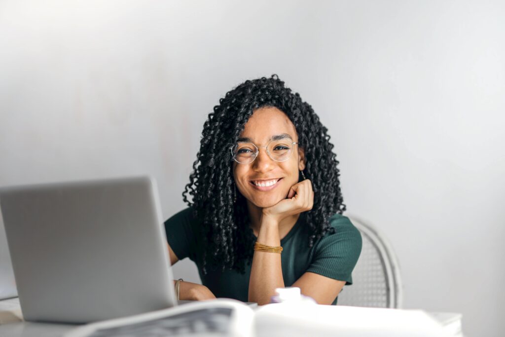 Happy woman sitting behind her laptop smiling