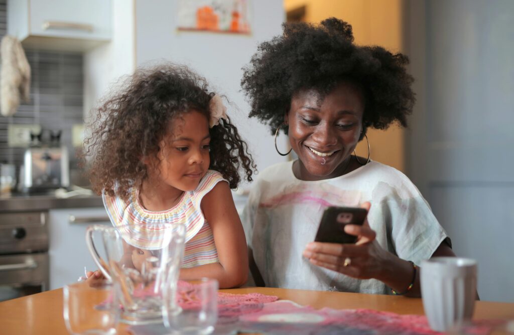 A young woman and her mother sitting together looking at the mother's phone.