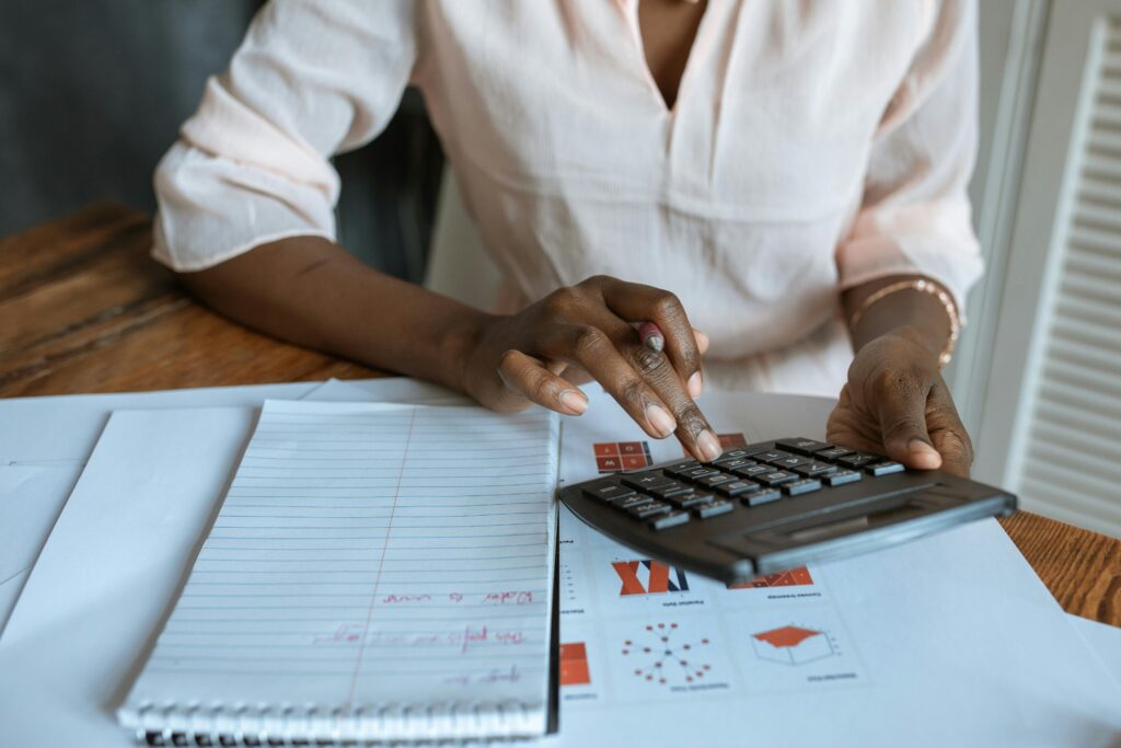 A woman sitting in front of papers and using a calculator
