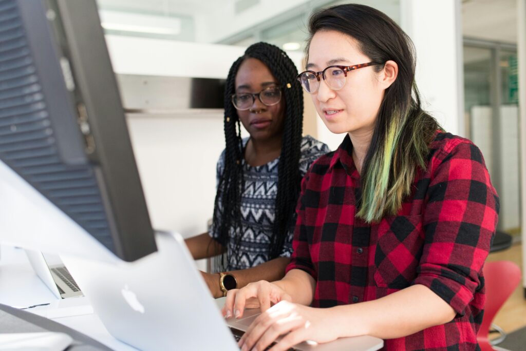 Two women sitting behind a computer screen learning together